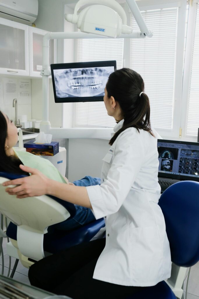 A dentist explains X-ray results to a patient in a modern dental clinic setting.