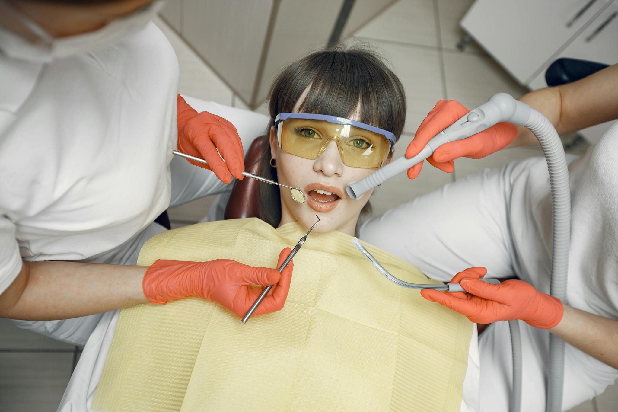 Dentist performing a checkup with protective gear and tools in a clinic.