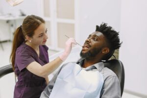 Female dentist examining a male patient in a modern dental clinic. Healthcare professionalism.